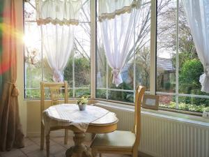 a table and chairs in a room with windows at Le Domaine des Prés du Hom in Bézu-Saint-Éloi