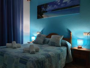 a bedroom with a bed with blue walls and two lamps at Pension los Verdiales in La Herradura +35 photos