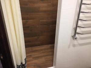 a bathroom with a shower curtain and a wooden floor at Apartment on Belvedere in Ivano-Frankivsʼk