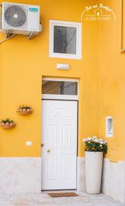 une maison avec une porte blanche et un mur jaune dans l'établissement b&b la corte in centro, à Caserte