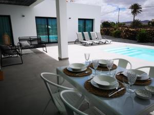 a table with glasses and plates on it next to a pool at Villa Montaña Colorada in Lajares