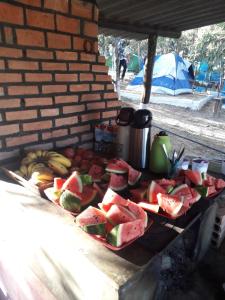 uma mesa com uma bandeja de melancia e fruta em Camping Avohai em São Tomé das Letras