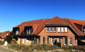 una casa de ladrillo con techo rojo en Ferienwohnung Baade -KEINE MONTEURE-, en Friedrichskoog-Spitz