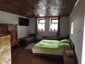 um quarto com uma cama verde e um sofá em Kontyos Vendégház em Felsőtold