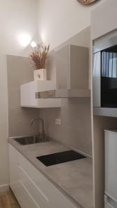 a kitchen with white cabinets and a sink and a microwave at Luxury Apartment In Triana Close To The River in Seville
