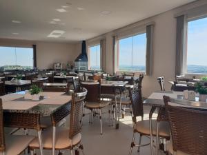 a restaurant with tables and chairs and windows at Hotel ITR-SPA in Itupeva