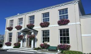 un bâtiment blanc avec des boîtes de fleurs sur les fenêtres dans l'établissement The Albany Apartments, à Saint-Pierre-Port