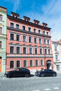 Deux voitures garées devant un grand bâtiment dans l'établissement Apartments Praha 6, à Prague