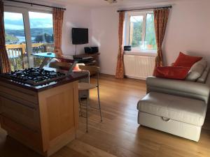 a kitchen with a stove and a chair and a couch at Suncot Apartment in Salcombe