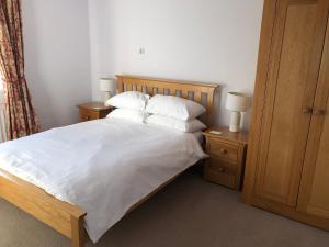 una camera da letto con letto, lenzuola e cuscini bianchi di Suncot Apartment a Salcombe