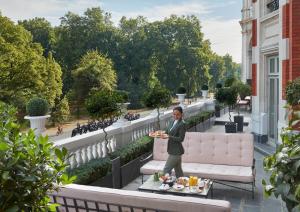 a man in a suit holding a plate of food on a balcony at Mandarin Oriental Hyde Park, London in London