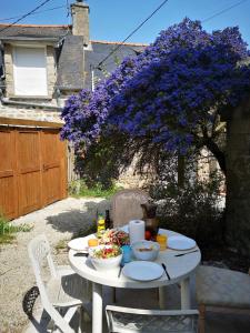 une table avec de la nourriture dans une cour avec un violet arbre dans l'établissement maison de pécheur typique presqu’île Saint Jacut Sur Mer, à Saint-Jacut-de-la-Mer