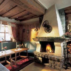 einen Kamin im Wohnzimmer mit einem Tisch und einem Tisch in der Unterkunft Hotel Garni Serfauserhof in Serfaus