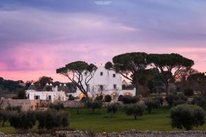 a white house in a field with trees at Masseria Grofoleo in Locorotondo