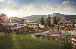a resort with a green yard with houses and mountains at Alpin Chalets Oberjoch in Bad Hindelang