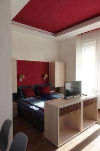 Frank & Fang Apartments MK7 في بودابست: غرفة نوم بسرير ومكتب مع تلفزيون