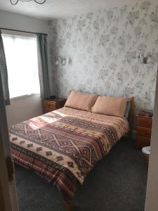 um quarto com uma cama com um cobertor e uma janela em Jacaranda Hotel em Paignton