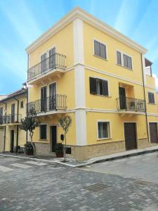 un grande edificio giallo con balconi su una strada di Scilla Resort a Scilla