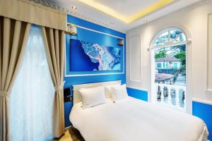 Un dormitorio azul con una cama blanca y una ventana en Dalat Boutique Hotel en Da Lat