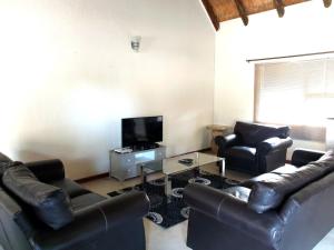 a living room with leather couches and a tv at Raptors Wildlife Escapes in Hoedspruit