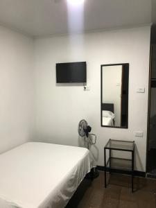 Habitación blanca con cama y espejo en Residencias la Marquesa 2 en Manizales