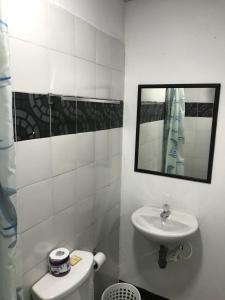 W łazience znajduje się umywalka, toaleta i lustro. w obiekcie Residencias la Marquesa 2 w mieście Manizales