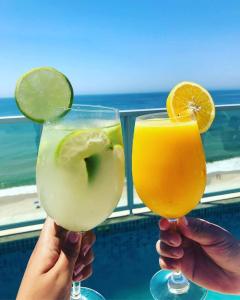 Duas pessoas a segurar dois copos de margaritas. em Hotel Brisa Tropical De Macaé em Macaé