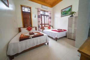 Un dormitorio con dos camas y una ventana. en Phong Nha Homestay, en Phong Nha