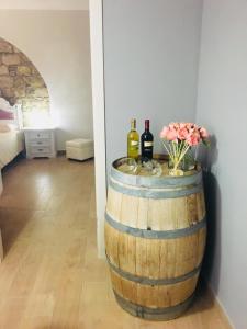 a barrel with two bottles of wine and a vase of flowers at Gesualdo da Venosa in Venosa