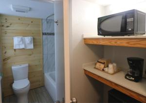 a bathroom with a toilet and a tv on a shelf at Howard Johnson by Wyndham Downtown Gatlinburg in Gatlinburg +25 photos