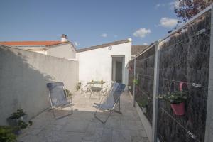 Un patio con sillas y una mesa y una valla. en la Patelle, en La Plaine-sur-Mer