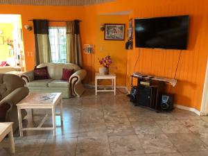 sala de estar con paredes de color naranja y TV de pantalla plana. en Whistling Villa Runaway Bay en Runaway Bay
