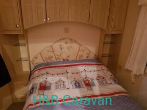 a bed in a room with a crib with a pillow at H&B Caravan on Marine Holiday Park in Rhyl