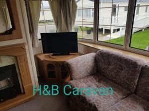 a living room with a couch and a television at H&B Caravan on Marine Holiday Park in Rhyl