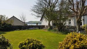a yard with a house and trees and flowers at 11 Laigh Isle in Isle of Whithorn