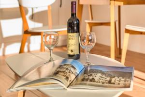 uma garrafa de vinho e dois copos numa mesa com um livro em Magical View em Kotor
