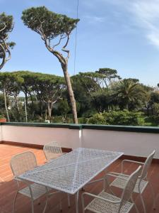 a table and chairs on a balcony with trees at Il Miraggio in Fregene
