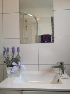 un lavabo con un jarrón de flores púrpuras. en Apartments Peloža, en Poreč