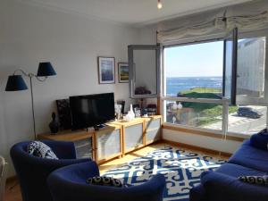 sala de estar con sillas azules y ventana grande en San Ciprián Playa y Mar by I Love Norte, en San Ciprián