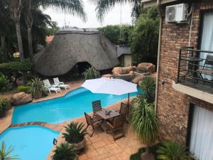 a swimming pool with a table and an umbrella at Francor Guesthouse in Pretoria +23 photos