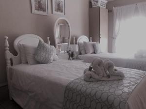 a bedroom with two beds with stuffed animals sitting on the ottoman at Elsje's Country Inn in Kempton Park