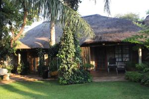 a house with a thatch roof with a yard at Francor Guesthouse in Pretoria