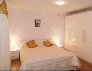a bedroom with a white bed with two pillows on it at Apartman Perina in Trogir