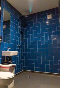 Baño de azulejos azules con aseo y lavamanos en PubLove @ The White Ferry, Victoria, en Londres