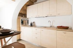 a kitchen with white cabinets and a sink at Dimora Via Vitti - Puglia Mia Apartments in Monopoli