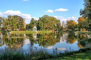 einen Teich in einem Park mit Pavillon und Bäumen in der Unterkunft Károlyi Kastély Hotel & Restaurant in Fehérvárcsurgó