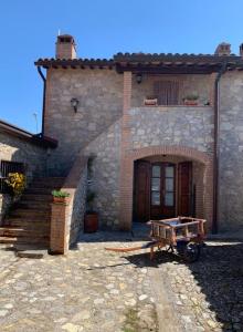 an old stone house with a wooden door and stairs at SAN COSTANZO APPARTAMENTI VACANZE in Parrano