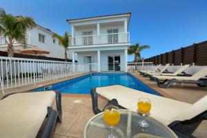 a villa with a swimming pool with a table and chairs at Nissi Villa Christa in Ayia Napa