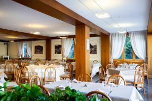 una sala da pranzo con tavoli e sedie bianchi di Hotel Ristorante Vapore a Faggeto Lario