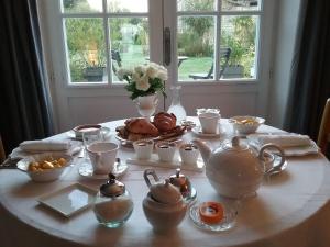 una mesa con un set de té con pastas y tazas en Chambre d'hôte le 18-20, en Saint-Martin-des-Entrées